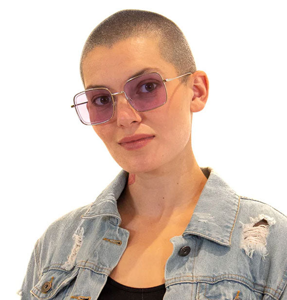 Model with shaved head wars a pair of square silver sunglasses with light purple lenses