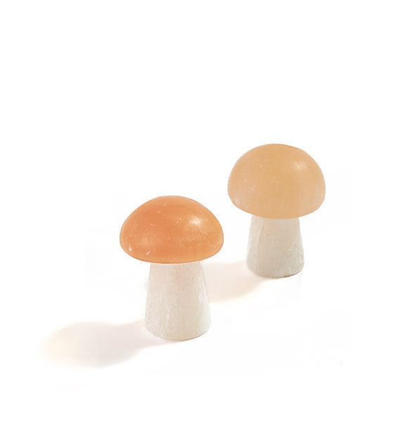 Pair of smooth stone mushroom figurines with peachy-colored tops and white bases