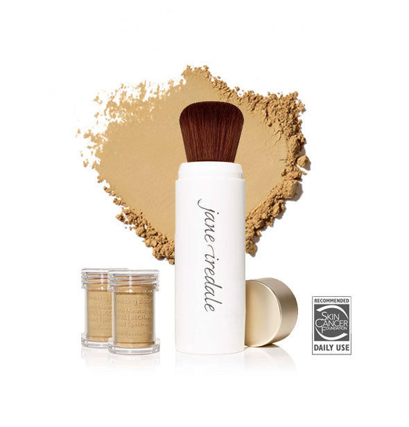 White Jane Iredale powder brush with gold cap removed and set to the side, two refill canisters nearby, and an enlarged product sample in the background in shade Latte