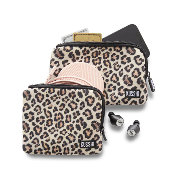 Two leopard print KUSSHI pouches, one square and one rectangular, with personal items appearing to fall out of each