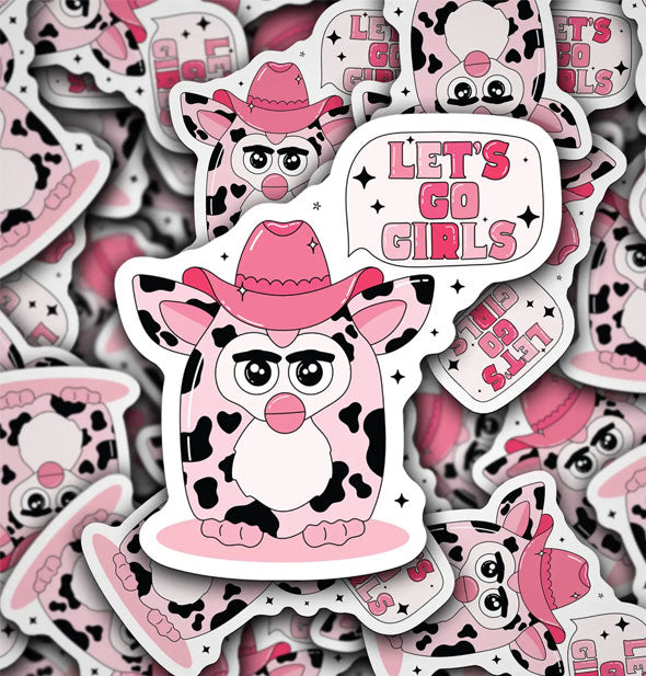 Pile of stickers with illustration of a pink cow-print Furby wearing a pink cowboy hat and saying, "Let's Go Girls" in pink lettering