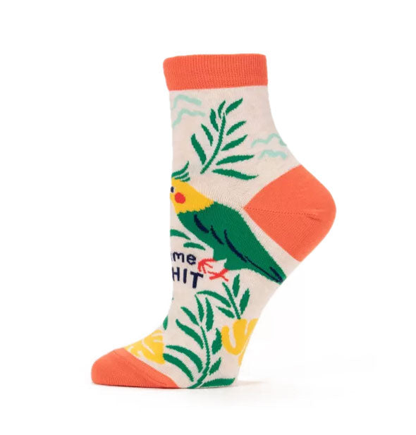 Beige ankle sock with orange top band, heel, and toe features tropical bird and ferns design with black lettering on the front