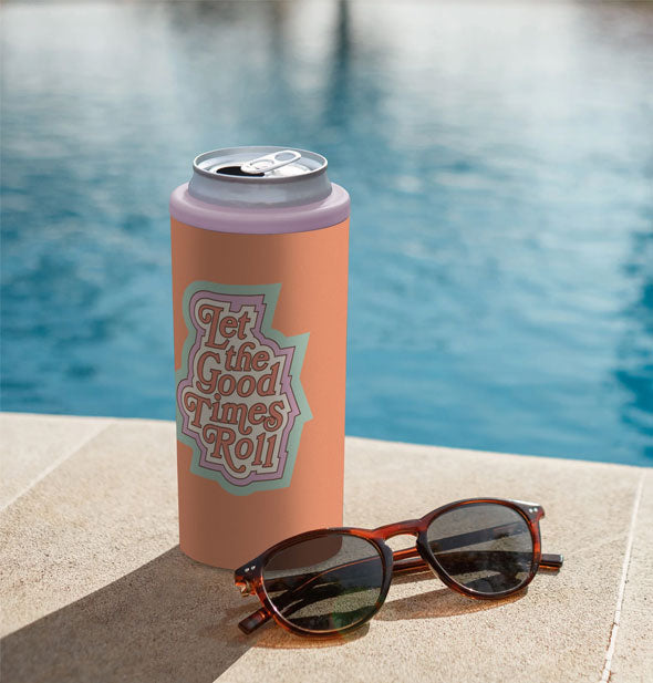 Let the Good Times Roll Slim Can Cooler rests on the edge of a pool with a pair of sunglasses