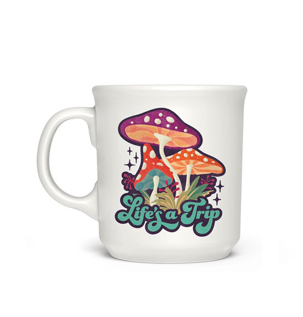 White coffee mug with colorful illustration of three mushrooms accented by greenery and stars says, "Life's a Trip" in retro-style script lettering