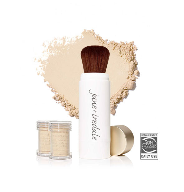 White Jane Iredale powder brush with gold cap removed and set to the side, two refill canisters nearby, and an enlarged product sample in the background in shade Light Beige