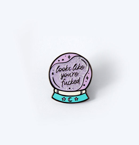 Enamel pin resembling a purple crystal ball with swirling sparkles on an aqua base says, "Looks like you're fucked" in script lettering