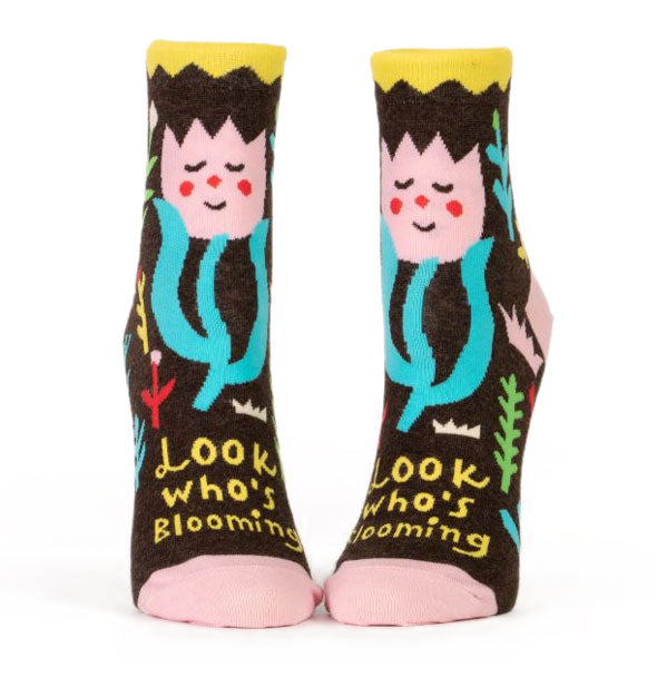 Pair of colorful \socks feature a blushing flower above the words, "Look who's blooming" in yellow on a dark backgroound