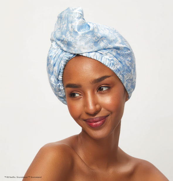 Smiling model wears a blue and white toile print satin hair wrap with elastic opening