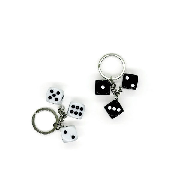Two keychains each with three dice attached—one white with black pips and the other black with white pips—on silver hardware