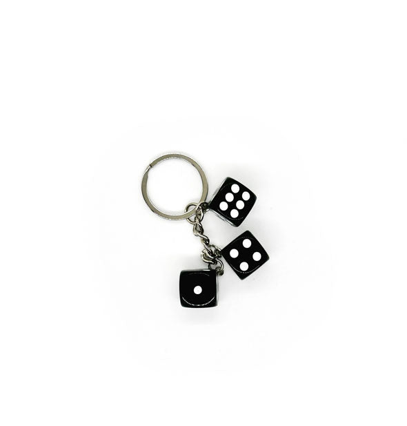 Three black dice with white pips on a silver keychain