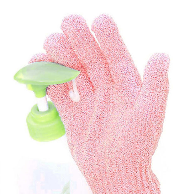 Cleanser is pumped into the balm of a textured pink exfoliating bath glove