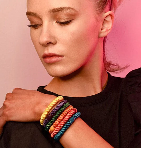 Model wears an assortment of colorful woven hair elastics with bead accents on left wrist