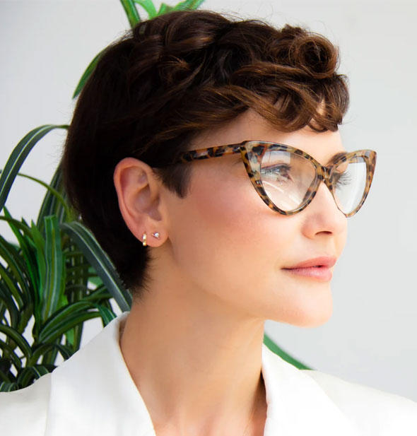 Model wears a pair of cat eye glasses with a brown animal print frame