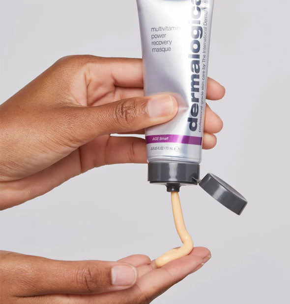 Model squeezes Dermalogica Multivitamin Power Recovery Masque from bottle onto fingertips