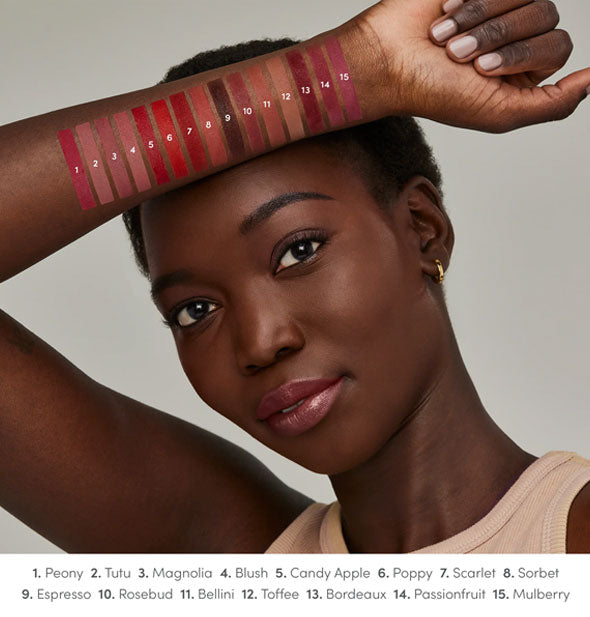 Model with dark skin tone holds forearm up to show each Jane Iredale ColorLuxe lipstick shade drawn on arm and labeled at bottom