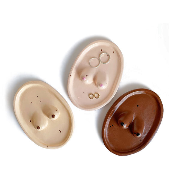 Pink, tan, and brown oval-shaped ceramic trays each with a pair of raised breasts