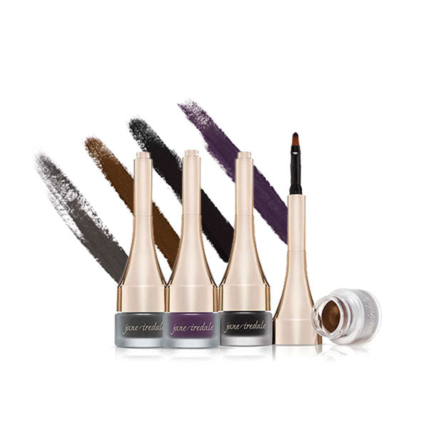 Grouping of Jane Iredale eyeliner pots with long golden lids, one of which is removed to show formula inside; streaked applications of each shade are behind bottles