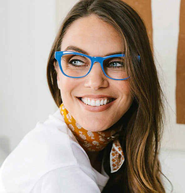 Smiling model wears a pair of blue squared cat eye reading glasses