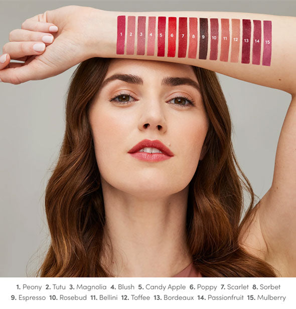 Model with light skin tone holds forearm up to show each Jane Iredale ColorLuxe lipstick shade drawn on arm and labeled at bottom