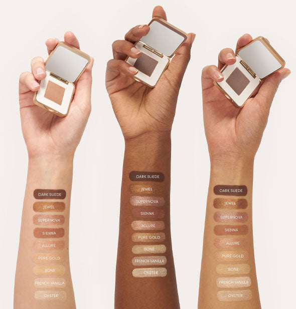 Three models' upraised hands holding Jane Iredale eye shadow compacts with inner forearms painted in each labeled shade