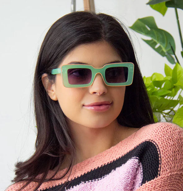 Model wears a pair of rectangular green sunglasses