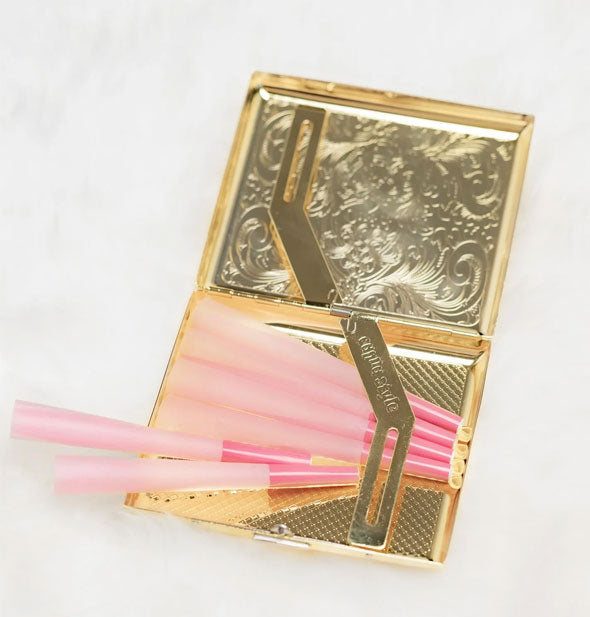 Decorative gold cigarette case shown open with pink rolling tubes inside under a holster