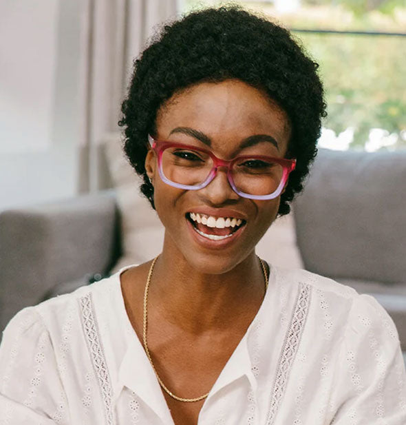 Smiling model wears a pair of pink and purple ombre glasses