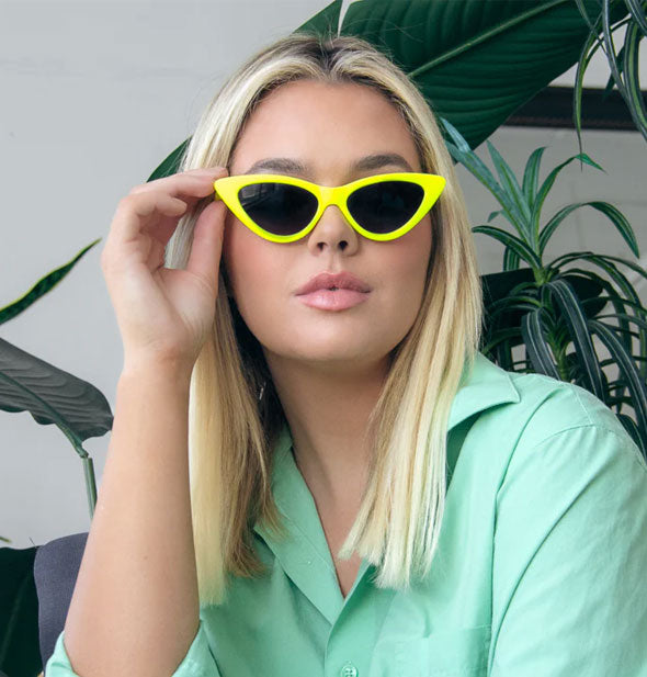 Model wears a pair of bright yellow cat eye sunglasses