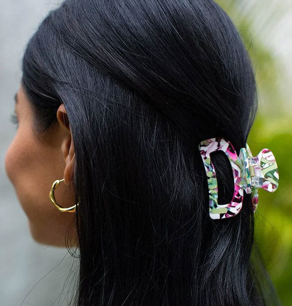 Model wears a colorfully flecked hair clip in a partially swept-back hairstyle