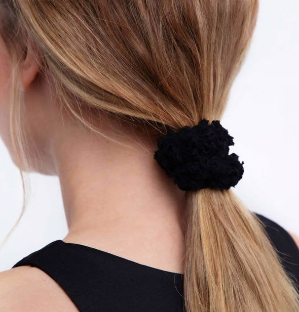Model wears a fluffy black cotton hair scrunchie in a low ponytail