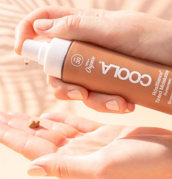 Model dispenses a dollop of Coola Rosilliance Tinted Moisturizer Sunscreen onto fingers