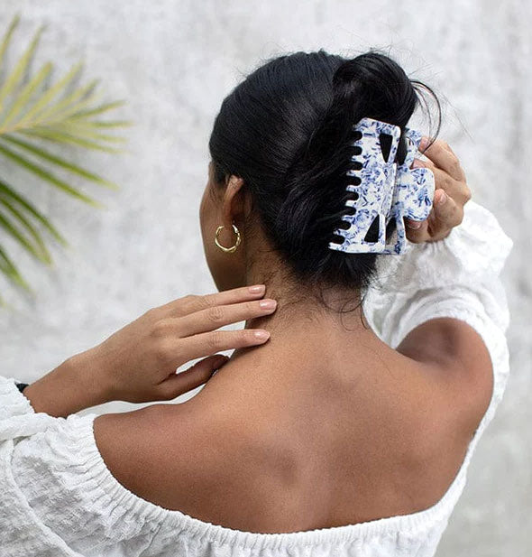 Model wears a large blue and white swirl pattern claw clip in a twisted updo