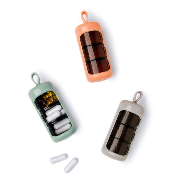 Green, orange, and gray pill cases with silicone hanging loops and black compartments