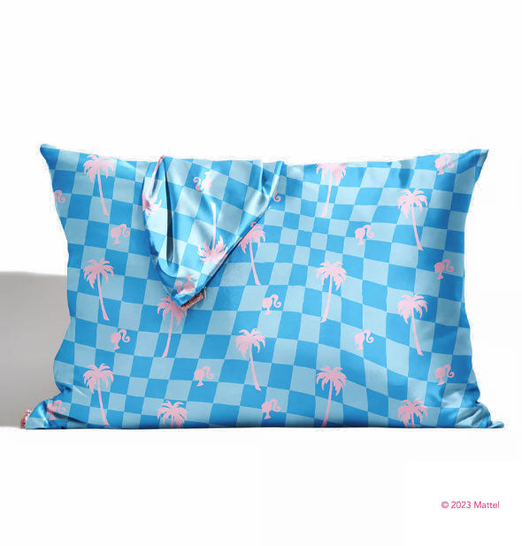 Pillow fitted with a blue wavy checker print pink satin pillowcase with pink palm tree and Barbie profile accents is draped loosey with another like it