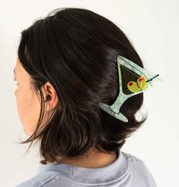 Model wears a hair clip designed to resemble a martini glass with olive garnish