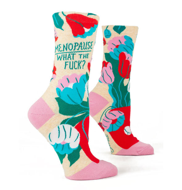 Pair of crew socks featuring bold, colorful floral designs and pink heels and toes say, "Menopause. What the fuck?" on the ankle