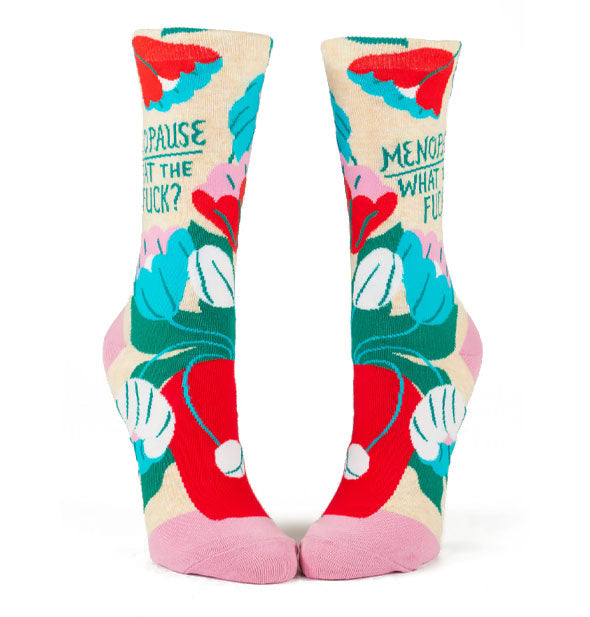 Pair of crew socks featuring bold, colorful floral designs and pink heels and toes say, "Menopause. What the fuck?" on the ankles