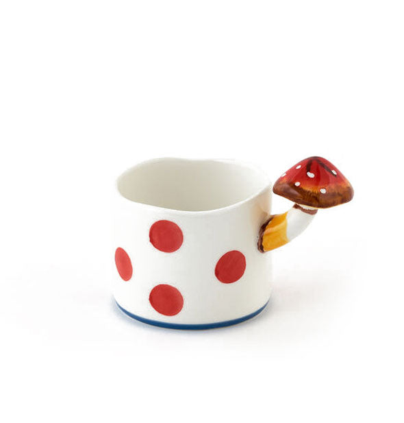 White ceramic mug with large red polkadots features a handle shaped and painted to resemble a mushroom