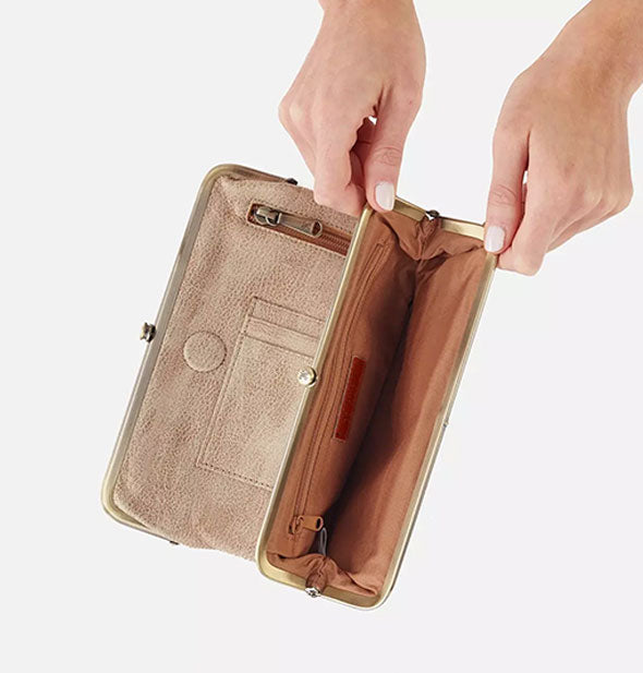 Model's hands hold open a section of a metallic gold wallet to reveal brown interior with an additional zipper pocket inside