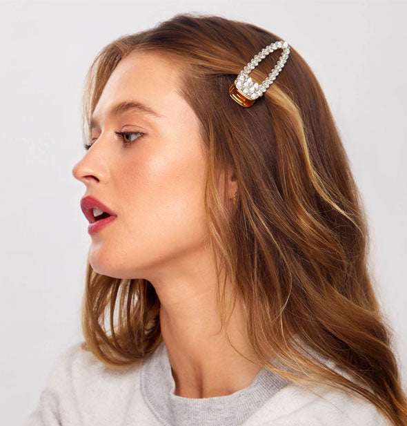 Model wears an oversized rhinestone-encrusted hair clip in a side-swept style