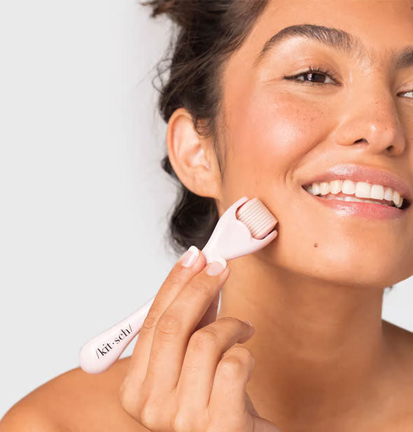 Smiling model demonstrates use of the Micro Derma Facial Roller by Kitsch on chin and cheek area