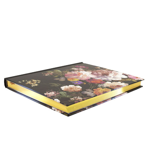 Three-quarter view of black journal with colorful floral pattern reveals gold page edges