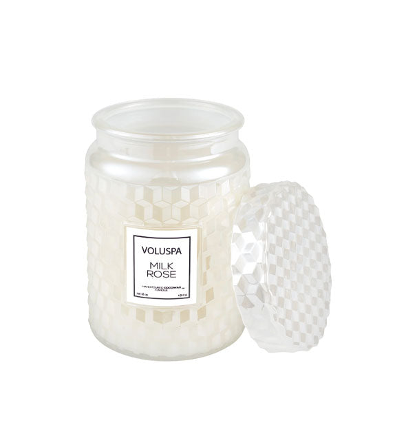 Pearlescent white textured Voluspa Milk Rose candle jar with matching lid removed and propped up alongside