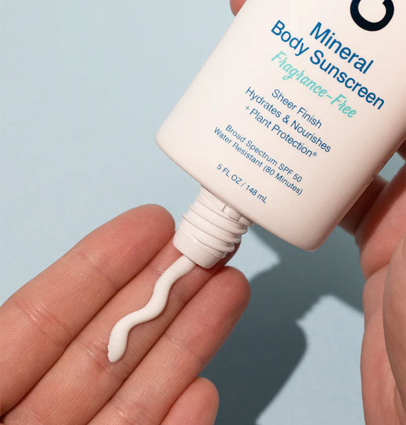 Model applies a squiggle of Coola Mineral Body Sunscreen to fingertip