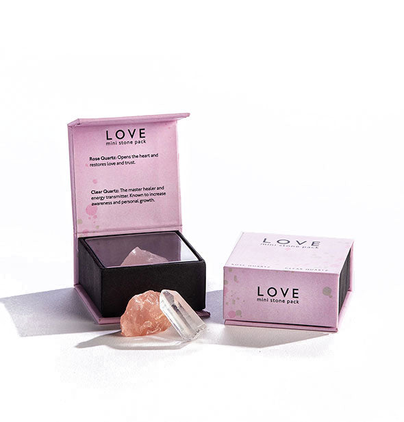 One closed and one opened pink box of Mini Stones for Love with chunks of clear crystal and rose quartz placed in front.
