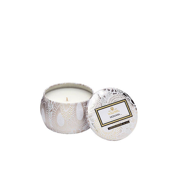 White and gold floral Mokara Voluspa candle tin with matching lid set to the side