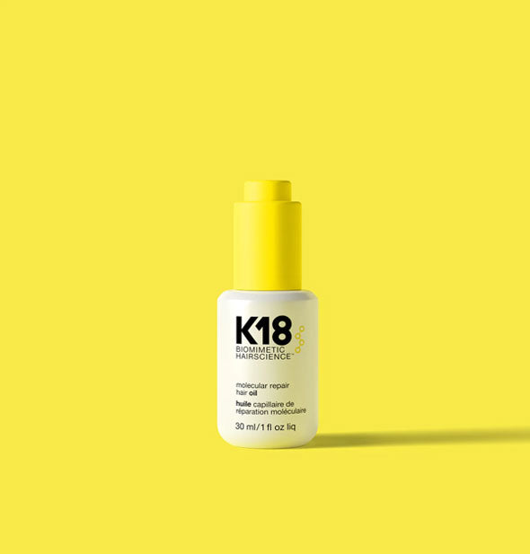 White 1 ounce bottle of K18 Biomimetic Hairscience Molecular Repair Hair Oil with orange cap on an orange background