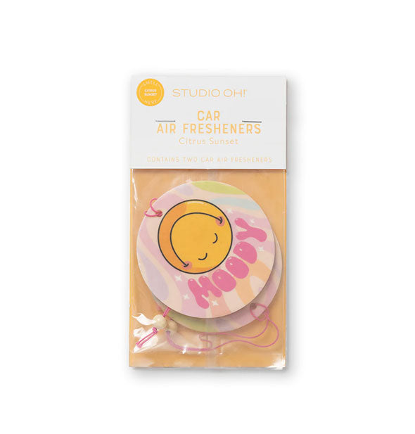 Pack of two round car air fresheners with yellow smiley faces say, "moody" in groovy pink lettering on a colorful tie dye-effect background