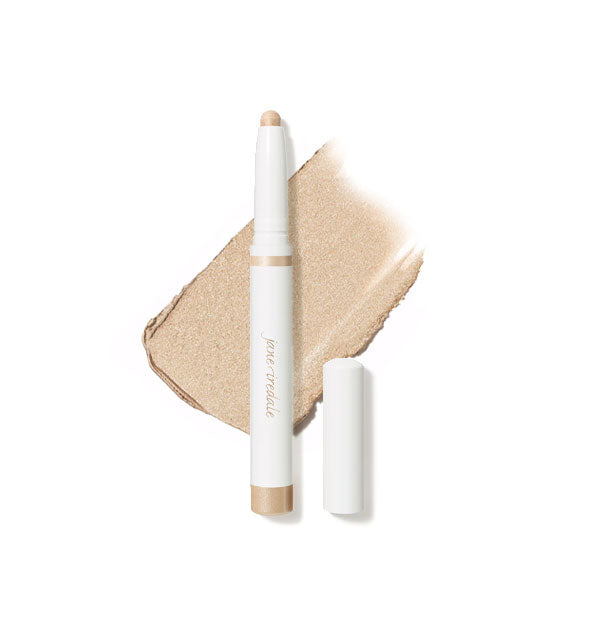 White stick of Jane Iredale eye shadow with cap removed to expose tip in front of a sample application of product in shade Moonstone