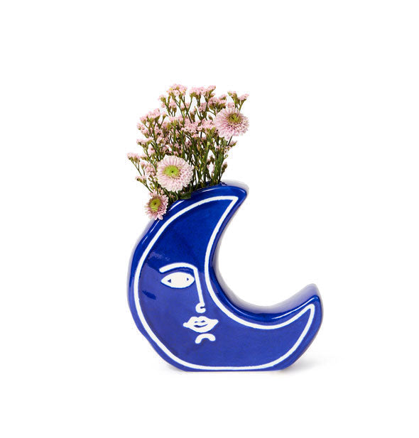 Blue crescent moon vase holds a bouquet of wildflowers